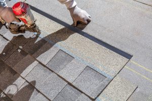 Close-up of a roofer's hands installing roofing upgrades on a residential roof with precision.